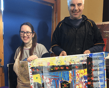 Photo of Simon Nailen and Angela Bishop holding up their colourful artwork