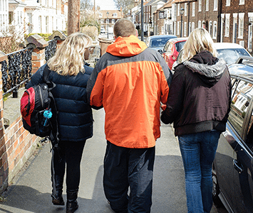 man walking down street with support workers